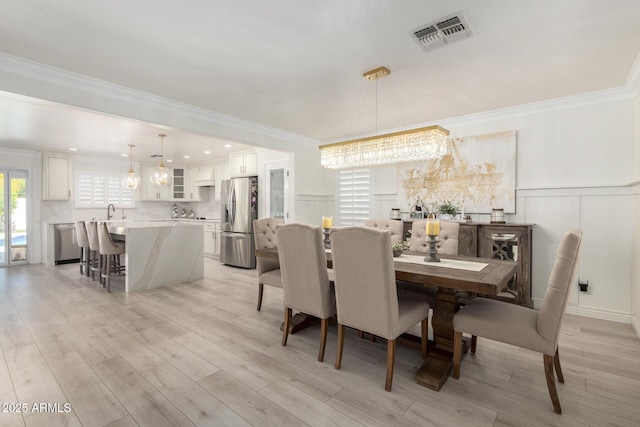 dining space featuring ornamental molding, an inviting chandelier, visible vents, and a decorative wall
