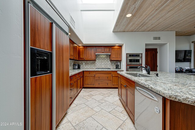 kitchen with light stone counters, stainless steel appliances, decorative backsplash, and sink