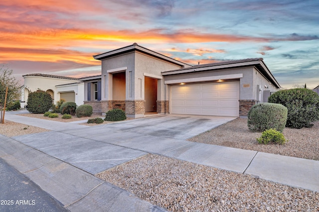 view of front facade with driveway, stucco siding, a garage, and brick siding