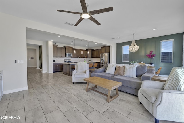 living room with ceiling fan with notable chandelier, visible vents, recessed lighting, and baseboards