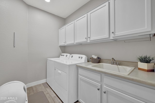 laundry room with washer and clothes dryer, wood finish floors, baseboards, a sink, and cabinet space