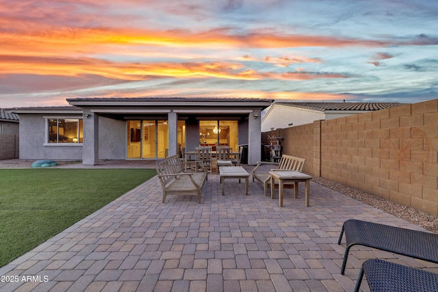 patio terrace at dusk featuring a lawn, a fenced backyard, and outdoor dining space
