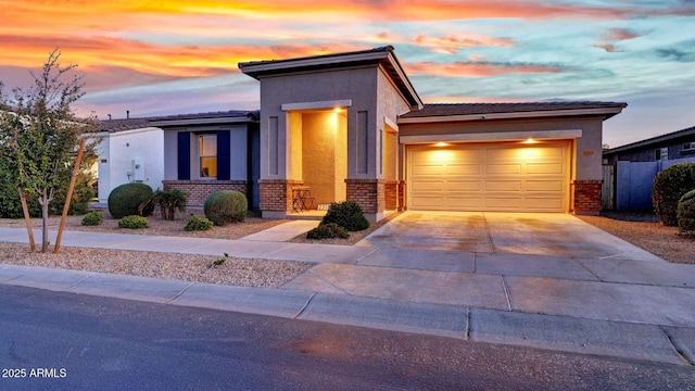 view of front of home with stucco siding, brick siding, a garage, and driveway
