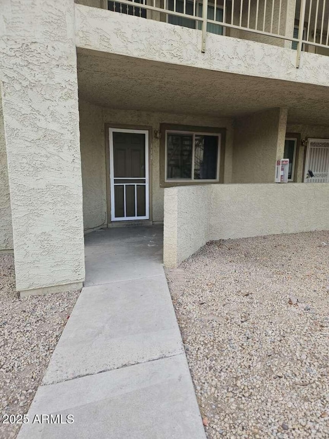 entrance to property featuring a balcony and stucco siding