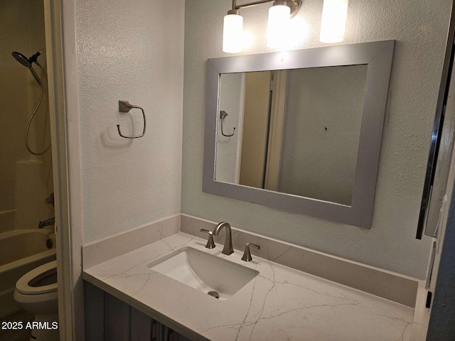 full bath with toilet, a textured wall, shower / tub combination, and vanity