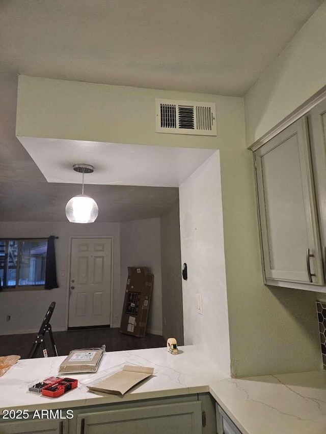 kitchen with decorative light fixtures, visible vents, and light stone countertops