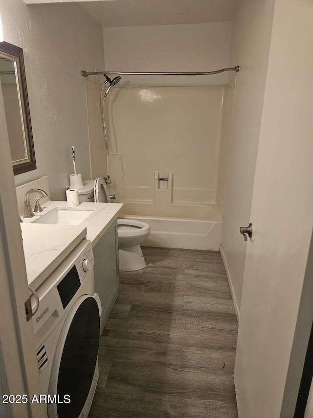 full bath featuring bathtub / shower combination, toilet, wood finished floors, vanity, and washer / clothes dryer