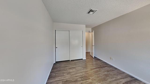 unfurnished bedroom featuring hardwood / wood-style flooring, a textured ceiling, and a closet