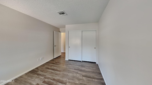 unfurnished bedroom featuring hardwood / wood-style floors, a closet, and a textured ceiling