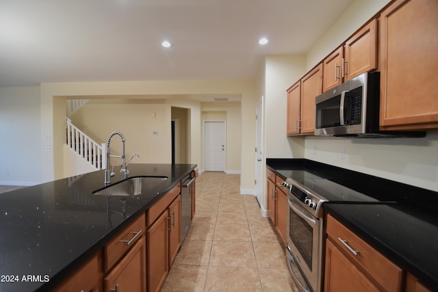 kitchen featuring sink, stainless steel appliances, dark stone countertops, and light tile floors