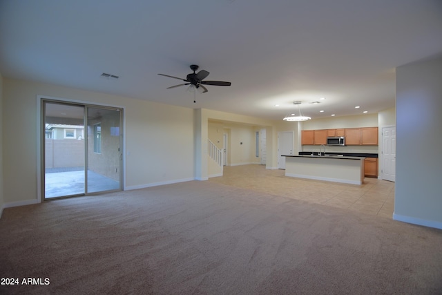 unfurnished living room featuring light carpet, ceiling fan, and sink