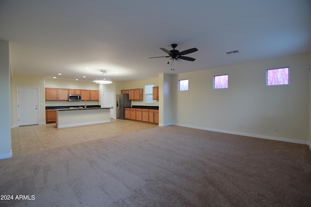 unfurnished living room featuring light colored carpet, ceiling fan, and sink