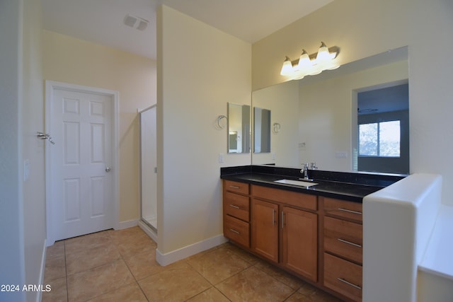 bathroom featuring tile flooring, a shower with shower door, and vanity