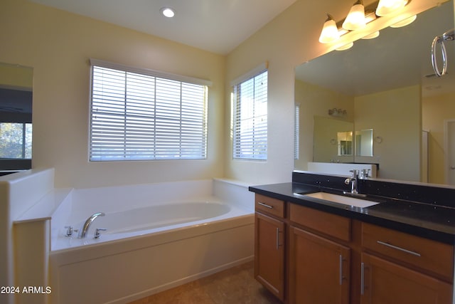 bathroom featuring a bath to relax in, a healthy amount of sunlight, vanity, and tile flooring