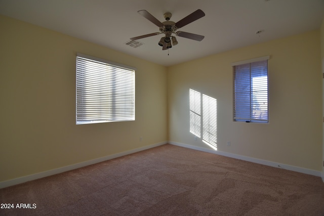 carpeted spare room with ceiling fan and plenty of natural light