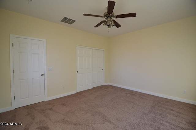 unfurnished bedroom featuring ceiling fan, light carpet, and a closet