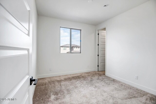 carpeted empty room featuring baseboards