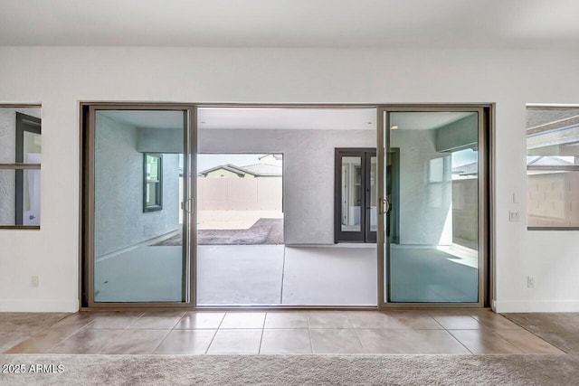 doorway to outside with light tile patterned flooring and baseboards