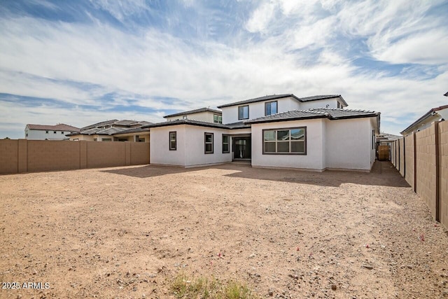 back of property featuring stucco siding, a tile roof, and a fenced backyard