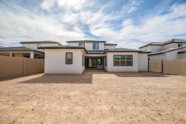 back of house with stucco siding and a fenced backyard