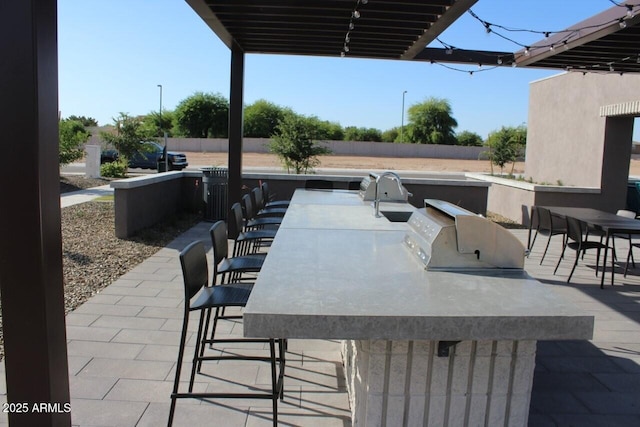 view of patio featuring outdoor wet bar, exterior kitchen, and fence