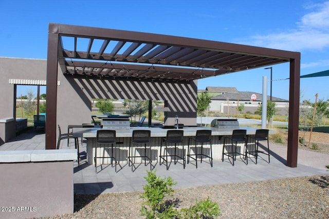 view of patio featuring outdoor wet bar, exterior kitchen, area for grilling, and a pergola