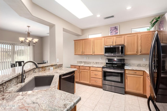 kitchen featuring decorative light fixtures, light stone countertops, sink, and black appliances