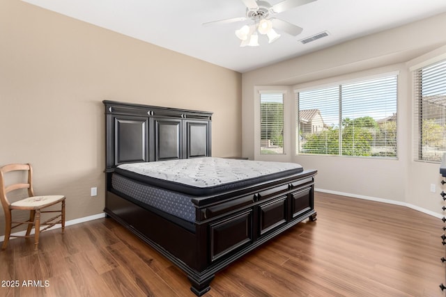 bedroom featuring multiple windows, dark hardwood / wood-style floors, and ceiling fan