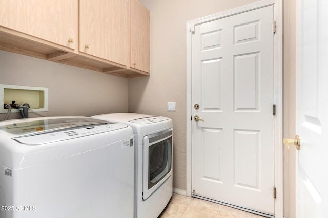 laundry area featuring cabinets, light tile patterned floors, and washing machine and clothes dryer