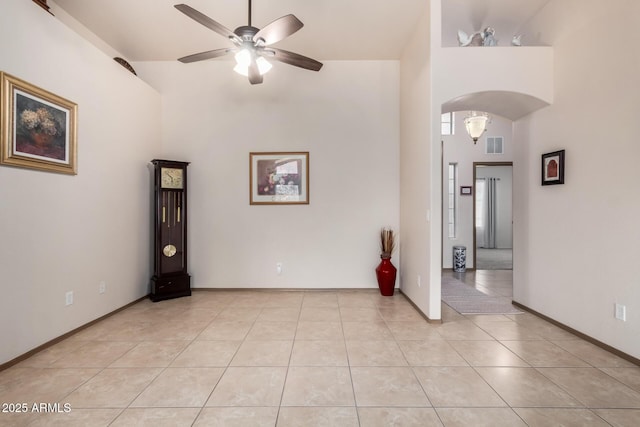 tiled spare room with a towering ceiling and ceiling fan