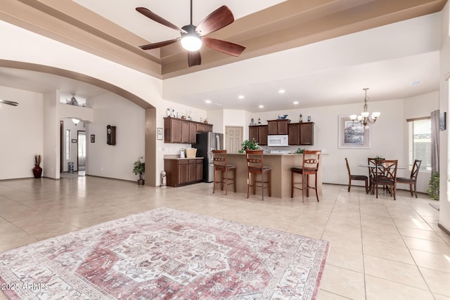 living room with ceiling fan with notable chandelier and light tile patterned flooring