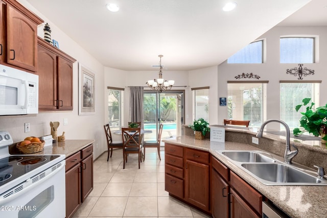 kitchen featuring sink, white appliances, light tile patterned floors, decorative light fixtures, and a chandelier