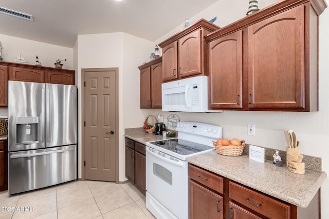 kitchen featuring light tile patterned floors, light stone counters, and white appliances