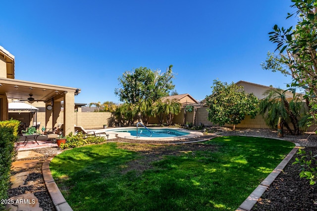 view of swimming pool with a yard and ceiling fan