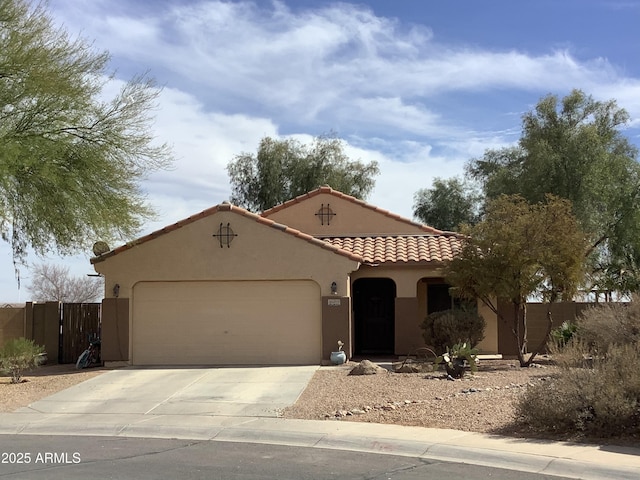 mediterranean / spanish home with a garage, fence, a tiled roof, driveway, and stucco siding