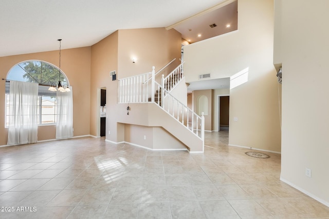 unfurnished living room with a notable chandelier, light tile patterned floors, and high vaulted ceiling