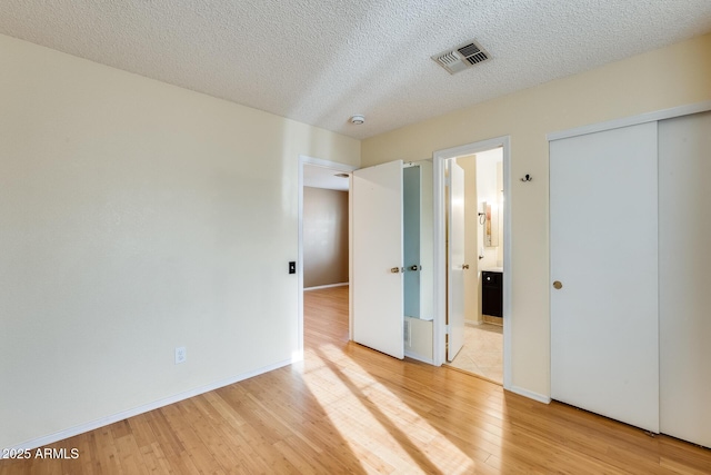 unfurnished bedroom with a closet, a textured ceiling, and light wood-type flooring