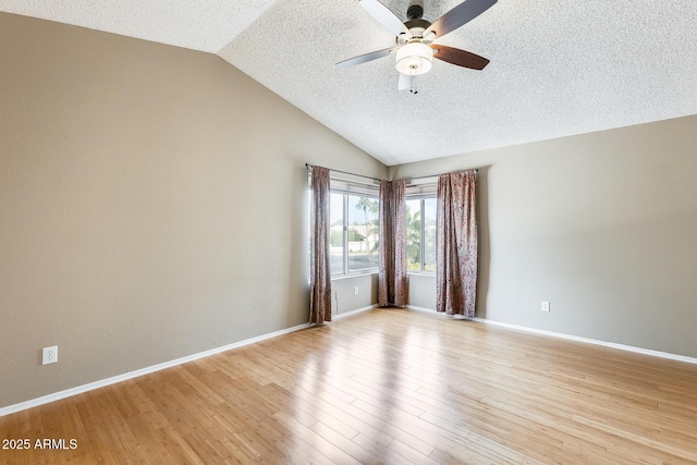 empty room with vaulted ceiling, a textured ceiling, ceiling fan, and light hardwood / wood-style floors