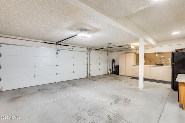 garage featuring a garage door opener, water heater, and black fridge