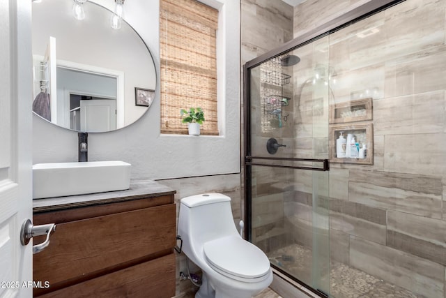 bathroom featuring vanity, toilet, and a shower with shower door