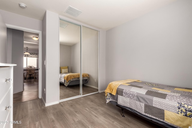 bedroom featuring a closet, wood finished floors, visible vents, and baseboards