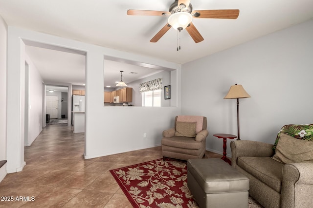 living area featuring a ceiling fan, tile patterned flooring, and baseboards