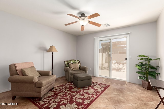 living area with light tile patterned floors, ceiling fan, visible vents, and baseboards