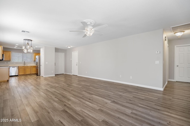 unfurnished living room featuring ceiling fan with notable chandelier and wood-type flooring