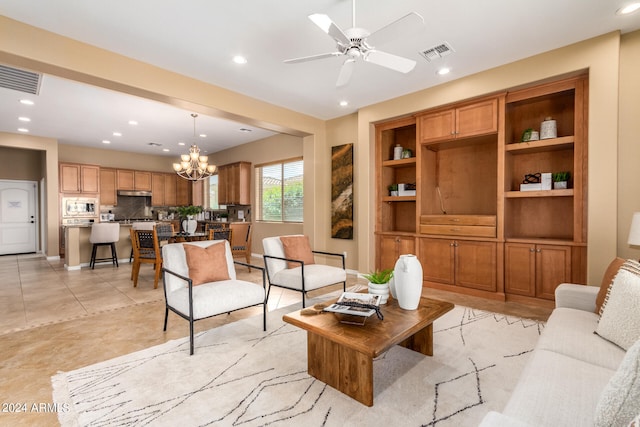 tiled living room with ceiling fan with notable chandelier and built in features