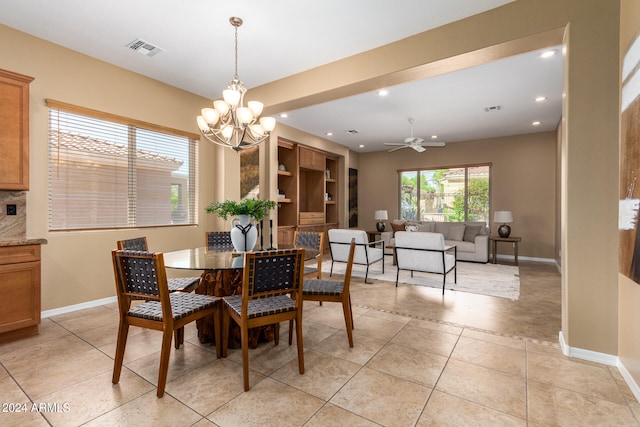 dining space with ceiling fan with notable chandelier and light tile patterned floors