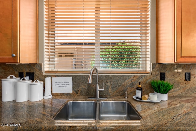 kitchen with dark stone counters, backsplash, and sink