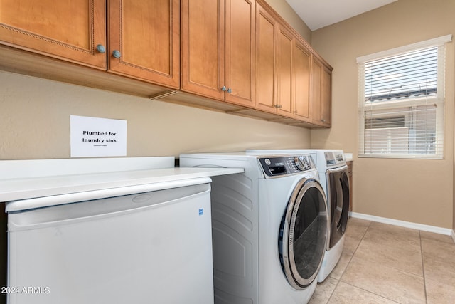 laundry area featuring washing machine and clothes dryer, cabinets, and light tile patterned floors