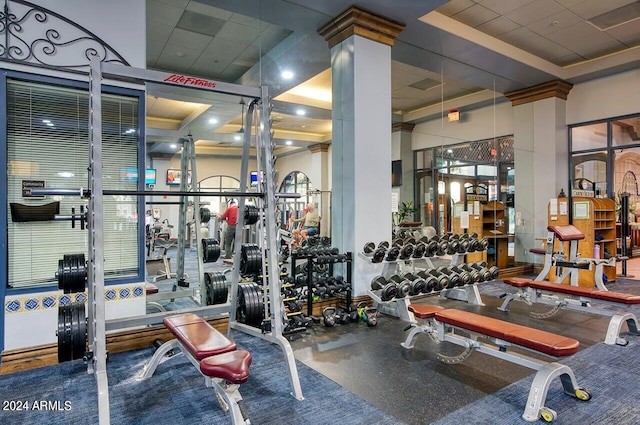 exercise room with a paneled ceiling and decorative columns