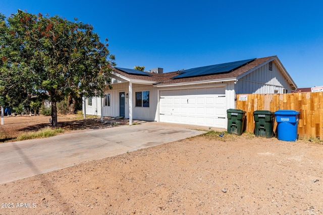 13039 N 19th Ave, Phoenix, AZ 85029 - view of front of home with a garage, concrete driveway, fence, roof mounted solar panels, and board and batten siding